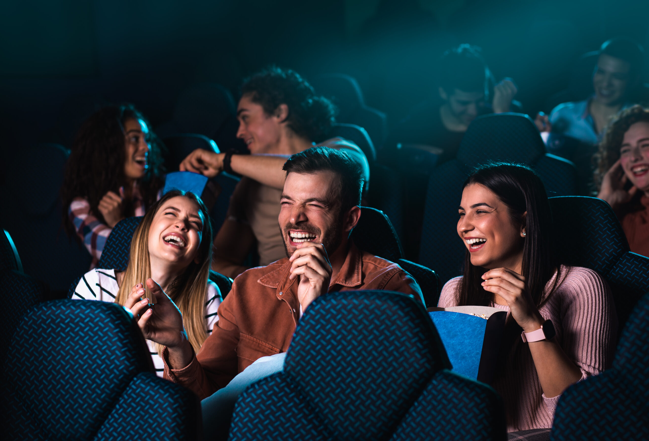 Group of cheerful people laughing while watching movie in cinema